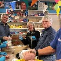 Volunteers smile for a photo while sorting food together.